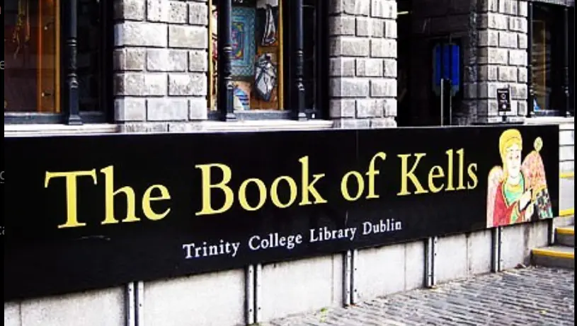 Entrance sign for the Book of Kells exhibit at Trinity College Library Dublin, featuring medieval-inspired artwork and lettering.